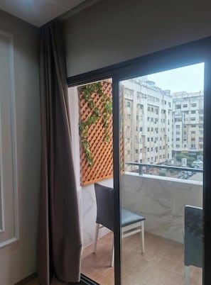 A balcony with a view of a cityscape, a wooden lattice wall with greenery, and a dining table with chairs. - Apartment in Marina de Tanger with a balcony (Tanger)