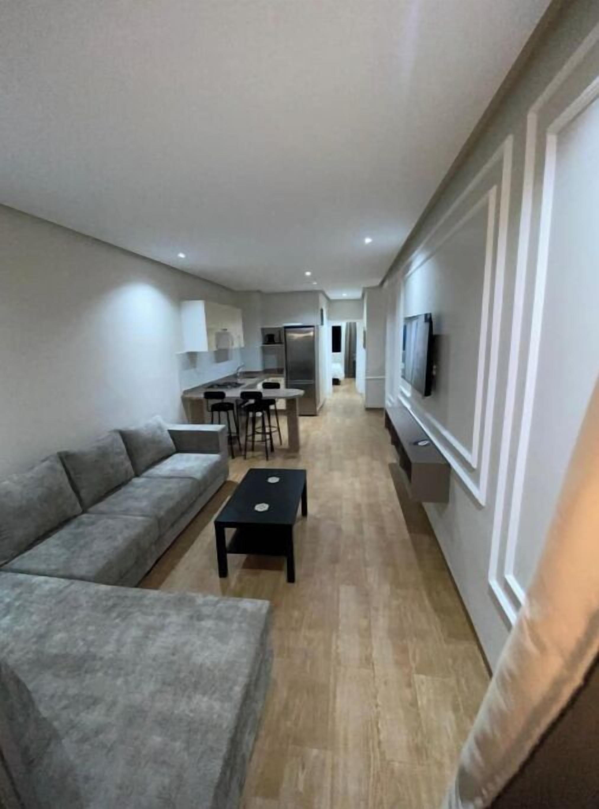 A modern living room with a sofa, a coffee table, and a TV mounted on the wall.