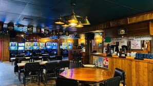 Un'area bar con diverse macchine da gioco, un bancone e posti a sedere.