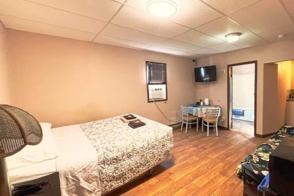 Una habitación de hotel con cama, escritorio, silla, televisor y sofá.