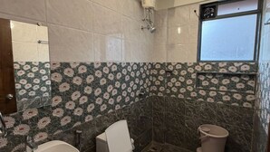 A bathroom with a bathtub, toilet, and bidet, featuring marble floors and floral-patterned tiles.