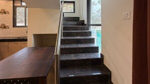 A modern staircase with a glass railing leading to a second floor.