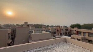 A residential area with multiple buildings, including a flat-roofed structure in the foreground and several multi-story buildings in the background.