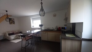 A modern kitchen with a dining area, a window, and a staircase.