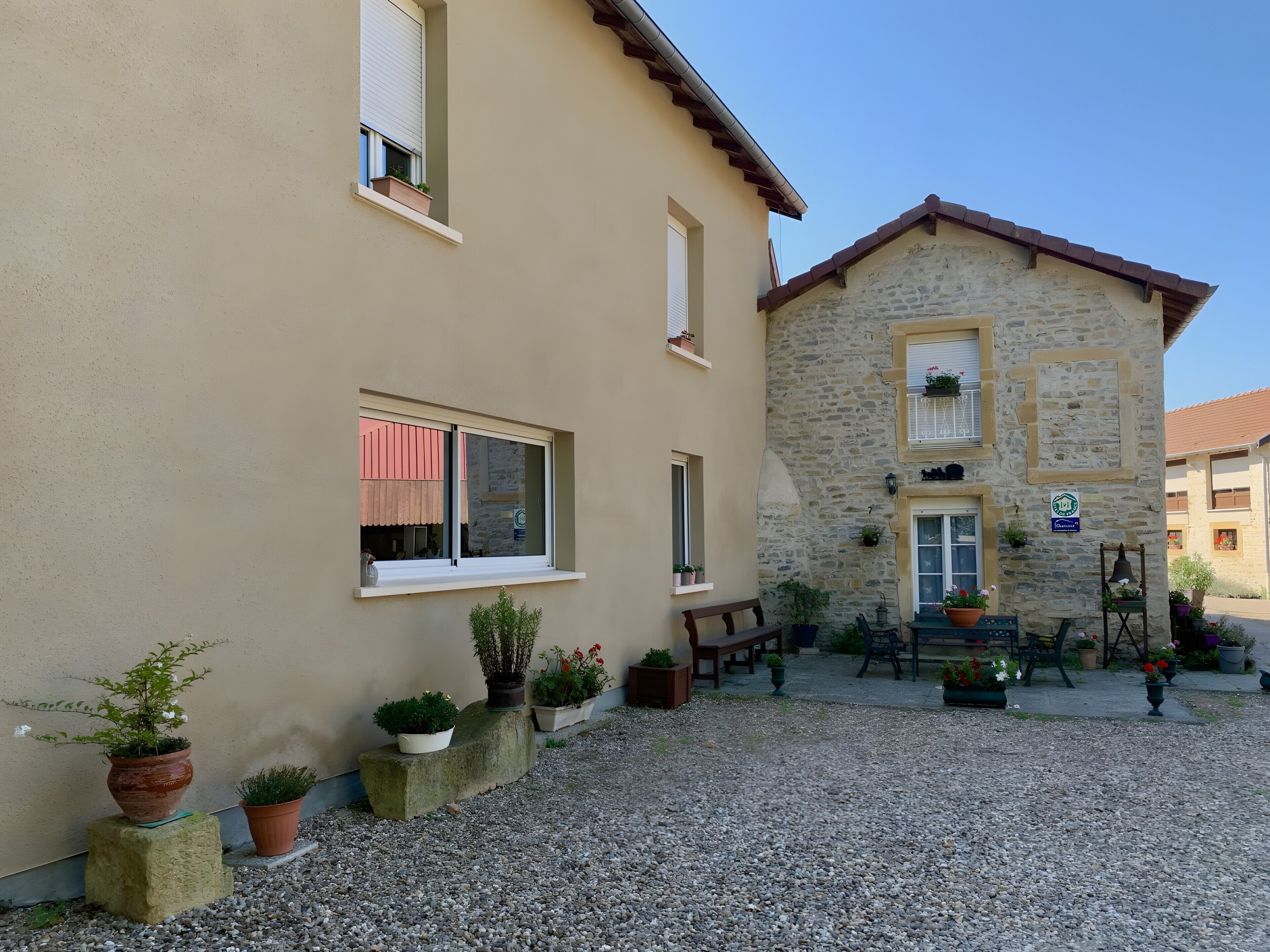 A building with a stone facade, multiple windows, and outdoor seating area with potted plants.