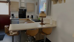A modern kitchen with a bar area, stainless steel appliances, and a decorative lamp.
