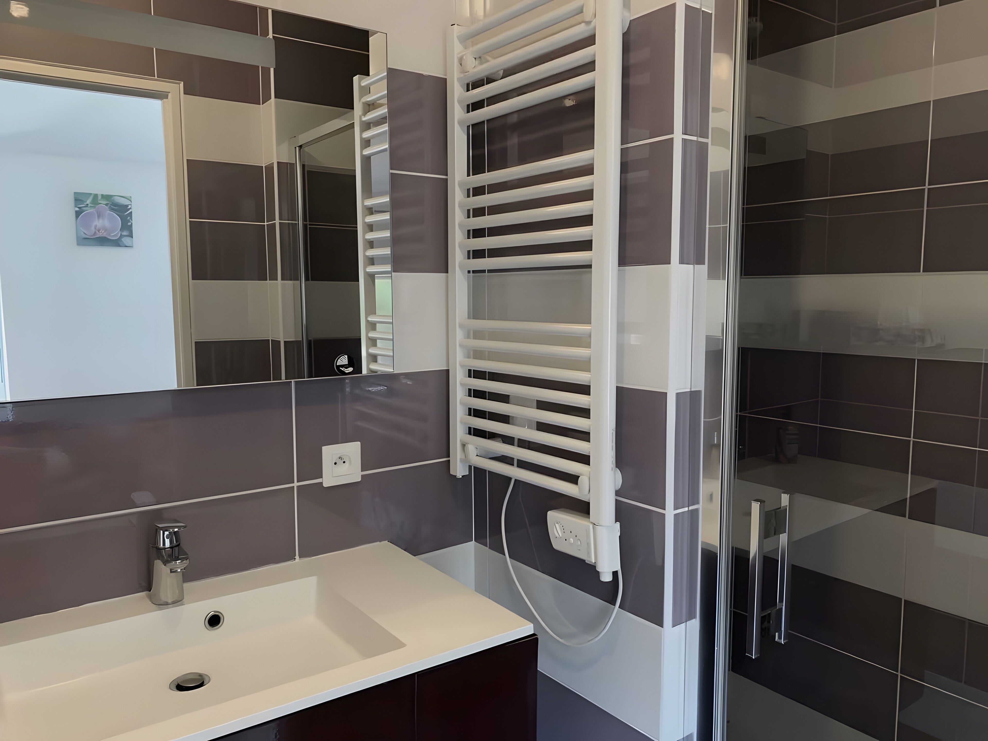 Ein modernes Badezimmer mit einem weißen Waschbecken, einem Spiegel und einem Handtuchhalter.