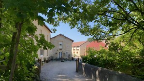A courtyard with a gravel path, stone buildings, and greenery.