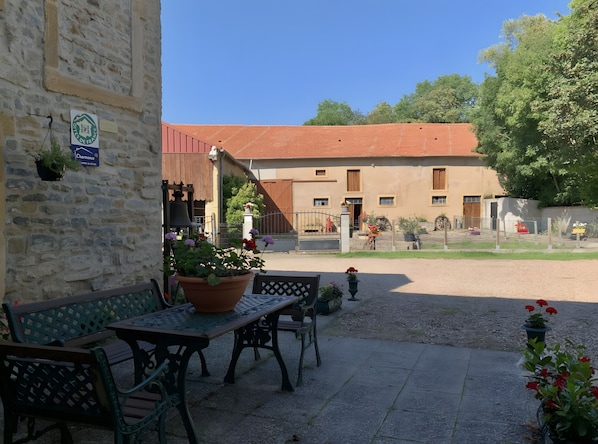 Ein Innenhof mit Steinmauer, einer Bank, einem Tisch und Blumentöpfen.