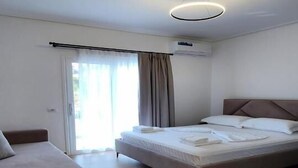 A modern hotel room with a bed, a sofa, and a sliding glass door leading to a balcony. - LBC Hotel (Sarandë)