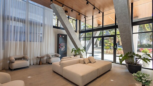 A modern interior with a sectional sofa, a small table, and potted plants. - Oxygen Batel (Curitiba)