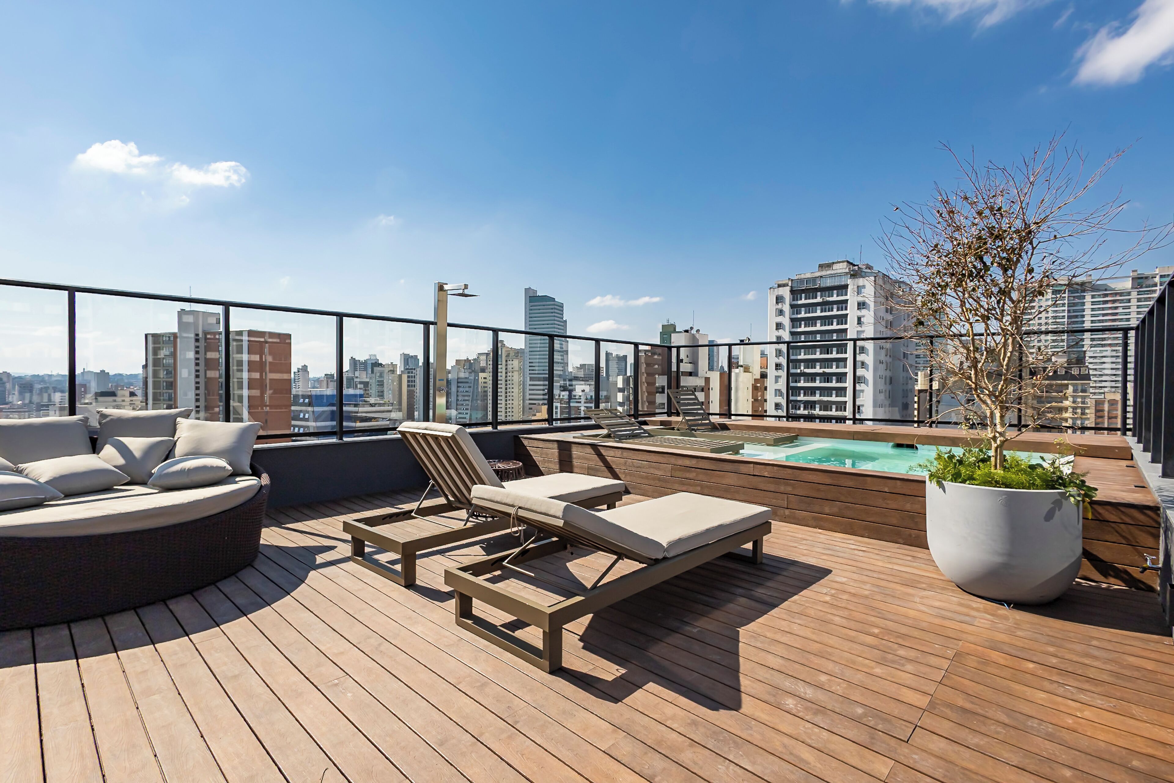A rooftop terrace with lounge chairs, a small pool, and a view of the city skyline.
