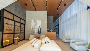 A modern interior with a large sectional sofa, a reception desk, and a wall with framed text. - Oxygen Batel (Curitiba)