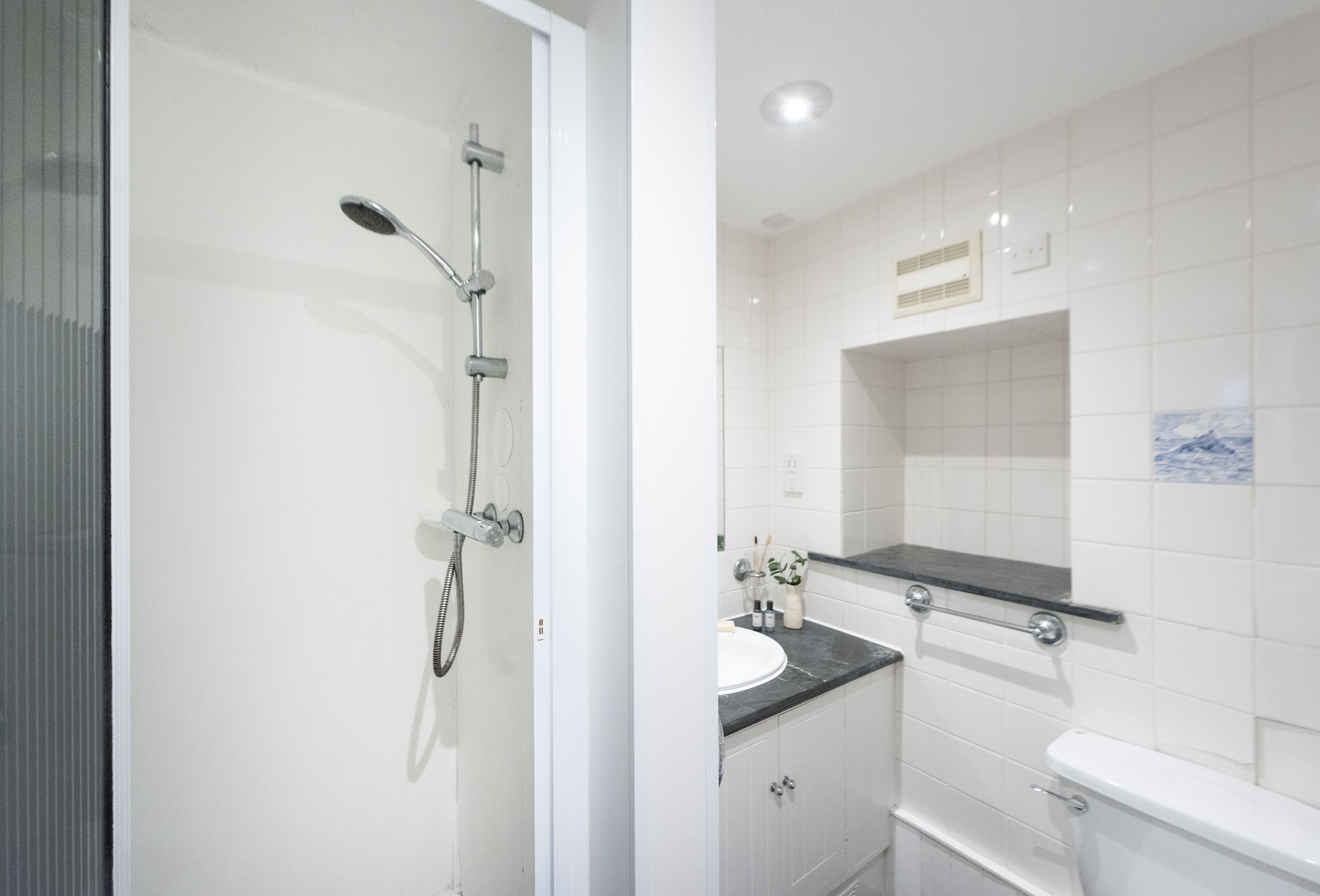 Uma casa de banho moderna com cabine de chuveiro em vidro, lavatório branco e sanita.