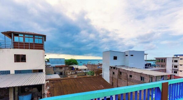 A coastal urban area with buildings, a view of the sea, and a cloudy sky. - Galapagos Home (Puerto Baquerizo Moreno)