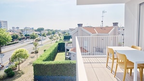 Un balcone con ringhiera bianca, un tavolo e sedie gialle.