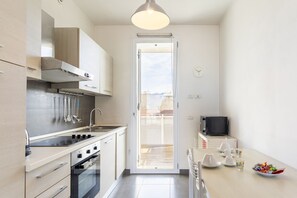 A modern kitchen with a stove, oven, and sink, a dining area with a table and chairs, and a TV on a stand.