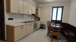 A kitchen with a sink, microwave, cabinets, and a dining area with chairs and a table. - Appartamento con 1 Camera da letto (Riva del Garda)