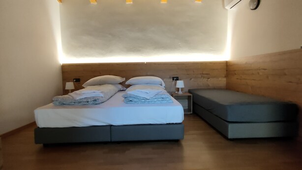 Un dormitorio con una cama, una mesita de noche y un pequeño sofá.