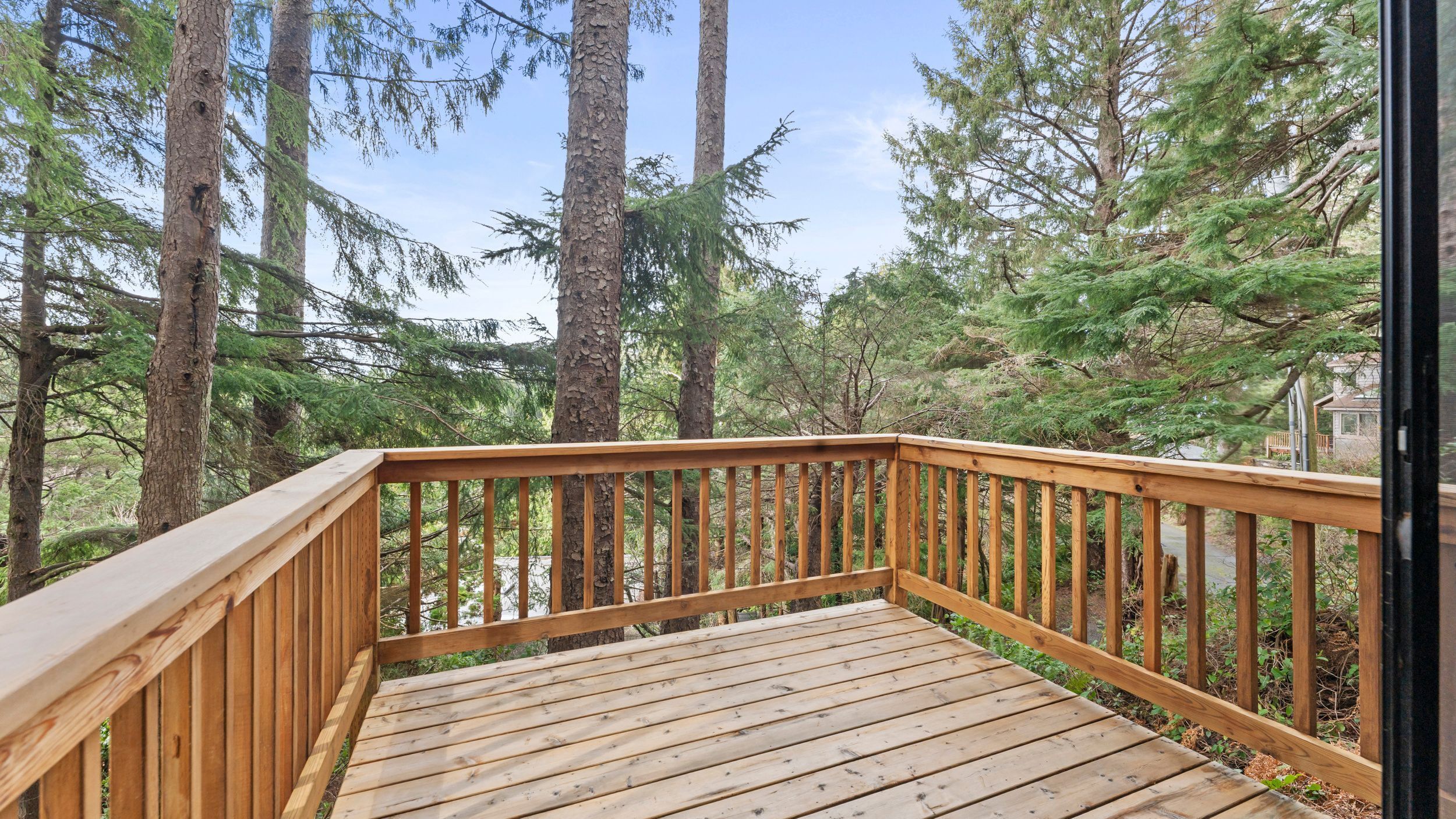 A wooden deck with railings overlooking a forested area.