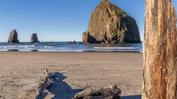 Una playa con grandes formaciones rocosas y un poste de madera en primer plano.