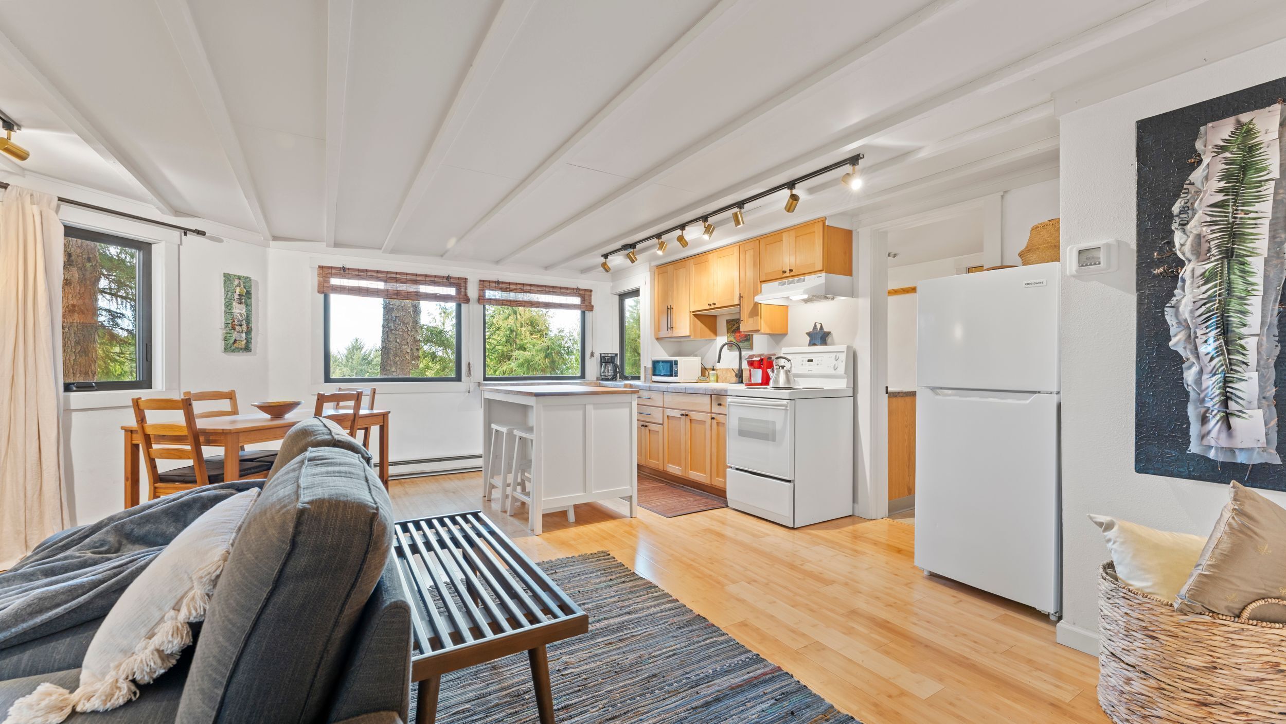 A modern kitchen with wooden cabinets, a white refrigerator, and a dining area with a wooden table and chairs.