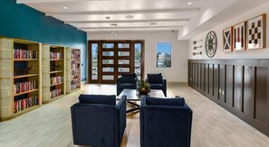 A library with bookshelves, a coffee table, two sofas, and a view through a glass door. - Landing Furnished Apartments near Lake Apopka (Apopka)