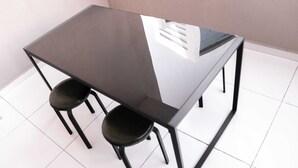 A modern table with a glass top and black metal frame, accompanied by two black chairs. - Stayshort - 1 Bed in Business Bay That Sleeps 4 Perfect for Everyone (Dubai)