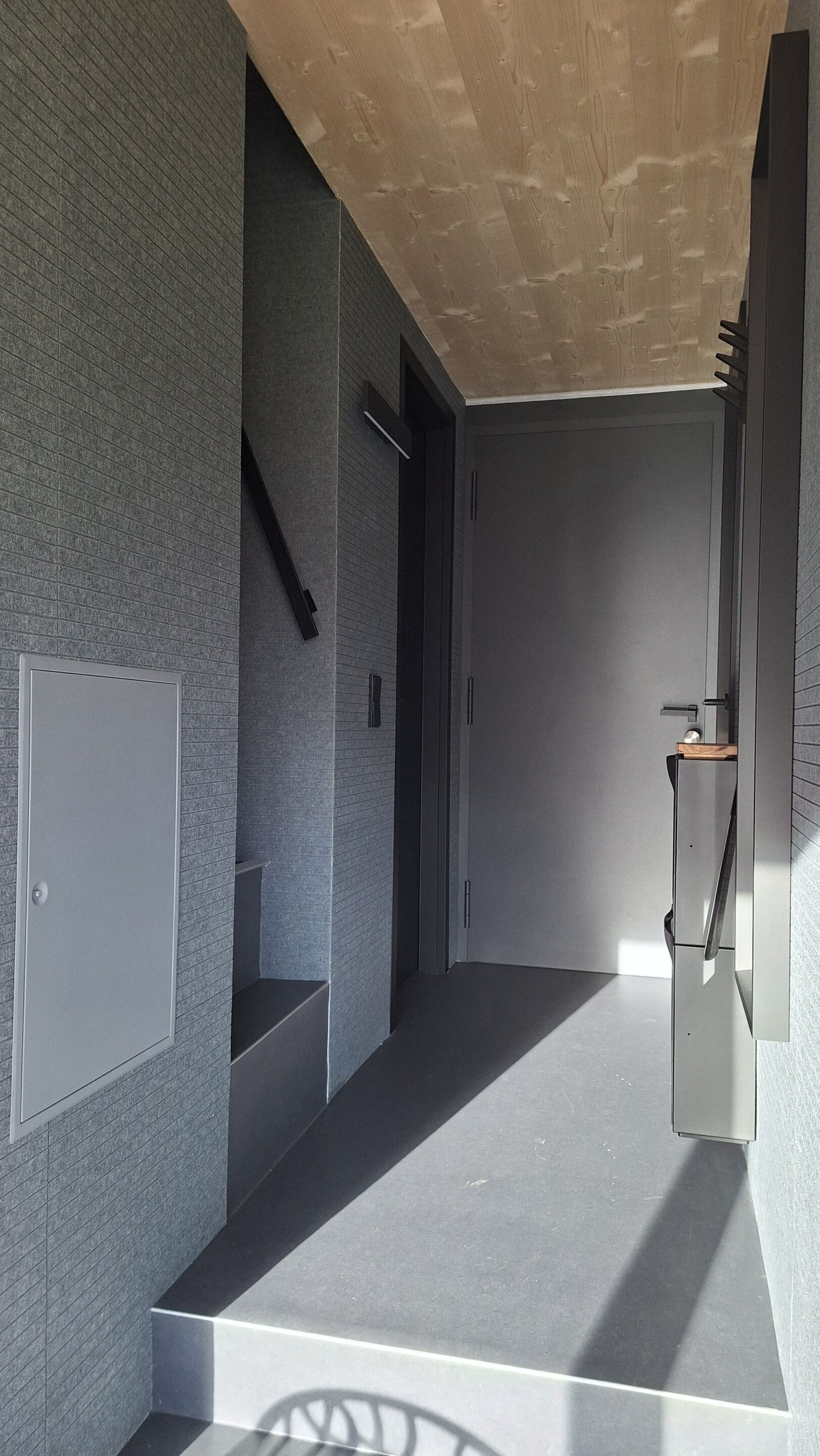 A modern interior with a staircase, a door, and a wall-mounted cabinet.