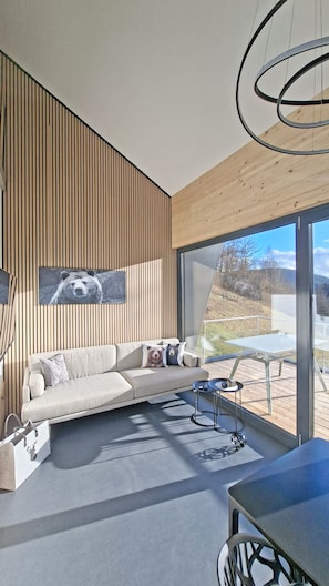Uma sala de estar moderna com um sofá, uma mesa de centro e um espaço de jantar com mesa de vidro.