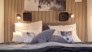 A bedroom with a bed, pillows, a wall-mounted picture, and two wall-mounted speakers. - SMART LODGES (Bad Rippoldsau-Schapbach)