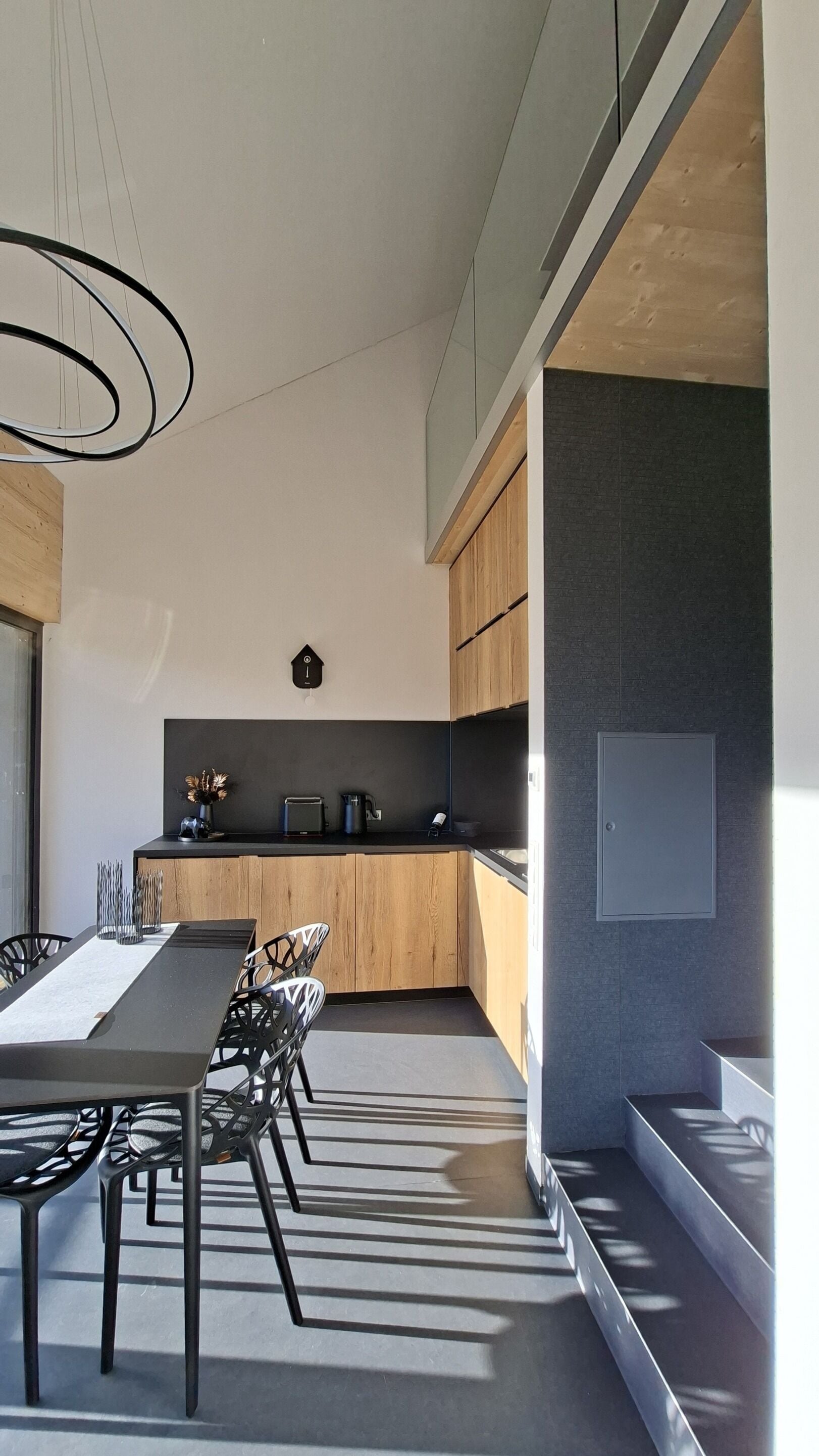 Una cocina moderna con una encimera larga, armarios de madera y una lámpara colgante.