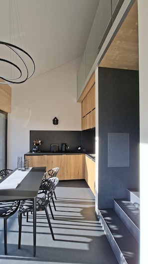 Cozinha moderna com bancada alongada, armários de madeira e luminária pendente.