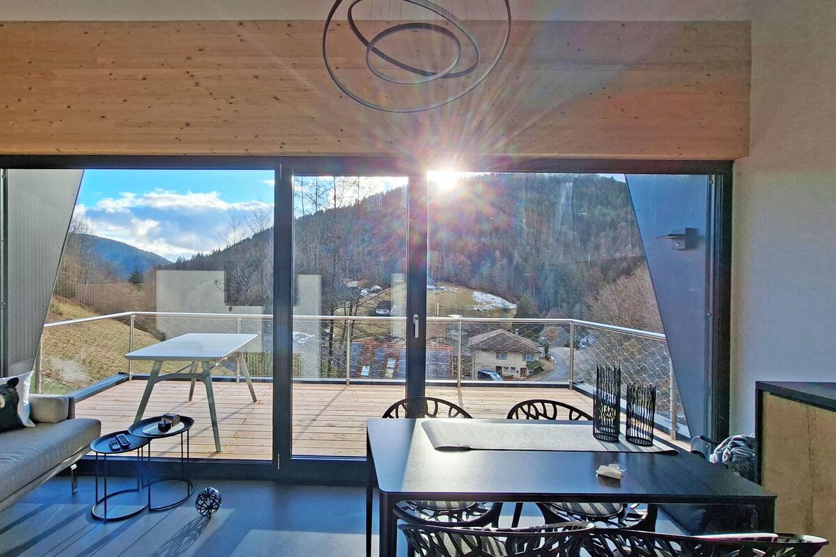 A modern interior with a balcony, a sofa, a table, and chairs.