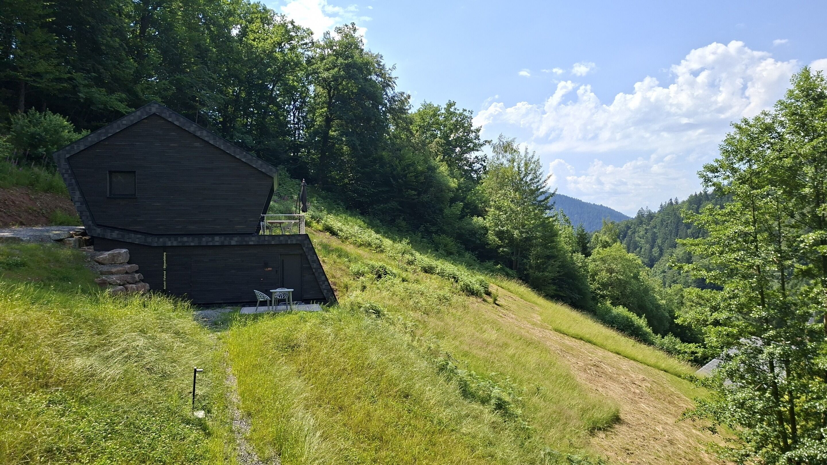 Une cabane rustique avec un toit en pente, une petite terrasse et des fondations en pierre.