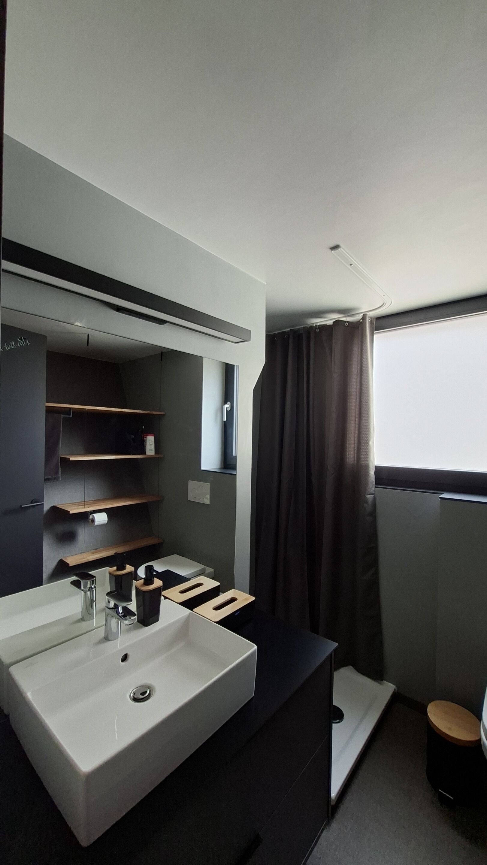 A modern bathroom with a large sink, mirror, and built-in shelves.