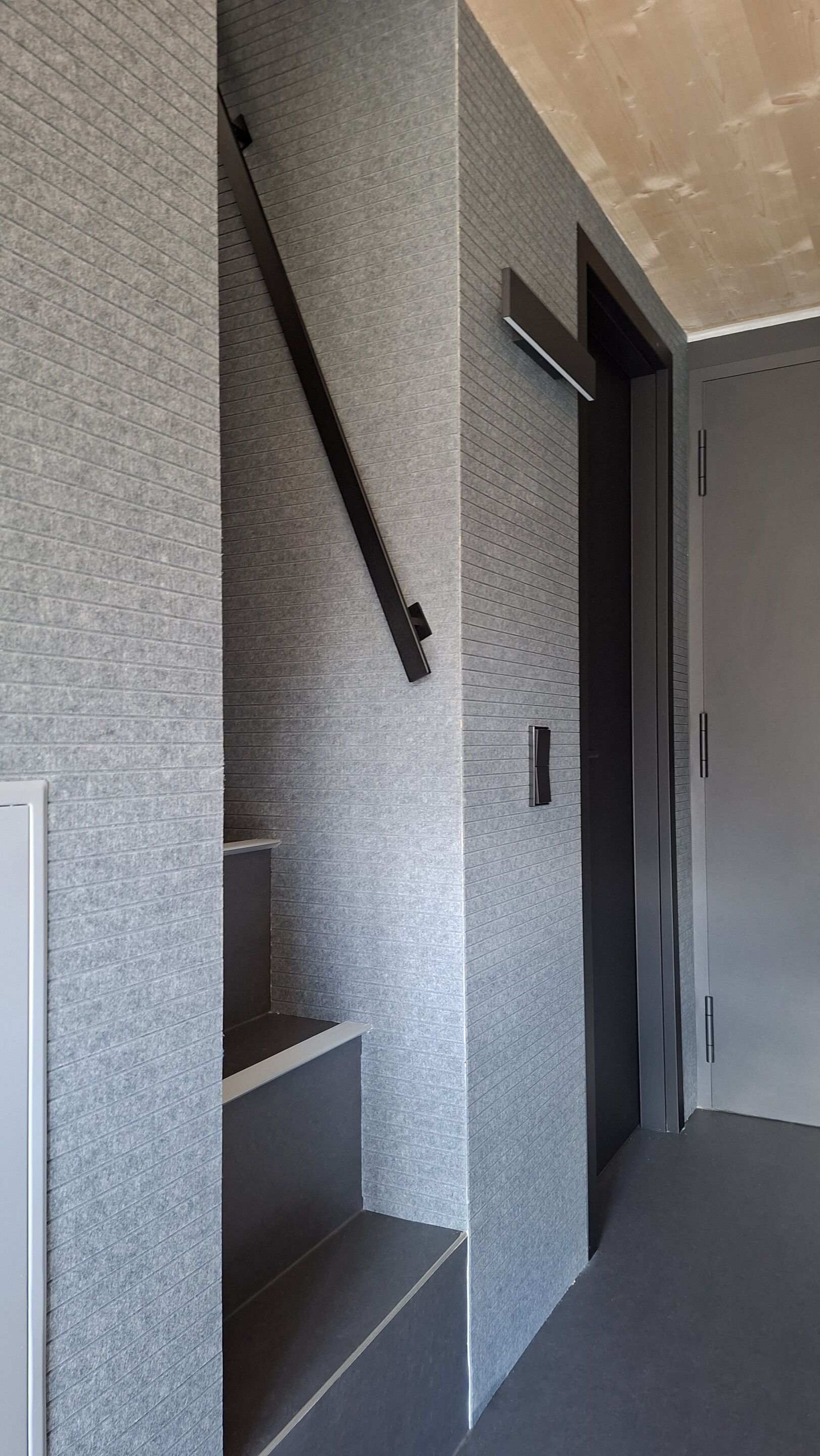 Een modern interieur met een trap, een deur en een wand met een structuur.