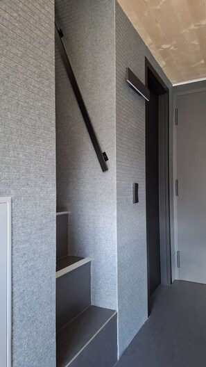 Un interior moderno con una escalera, una puerta y una pared con textura.