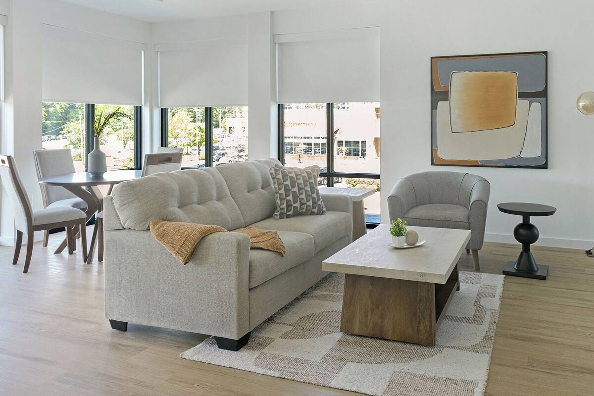 A modern living room with a sofa, armchair, coffee table, and floor lamp.