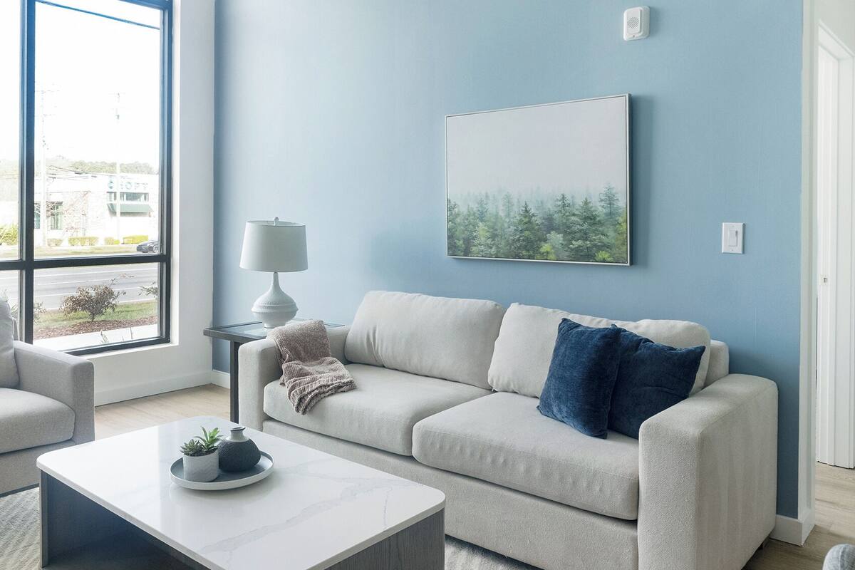 A living room with a sofa, a coffee table, a lamp, and a painting on the wall.