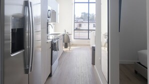 A modern kitchen with a stainless steel refrigerator, a built-in oven, and a microwave. There is a window providing a view of the outside. - Landing Apartments - Chapel Hill, NC (Chapel Hill)