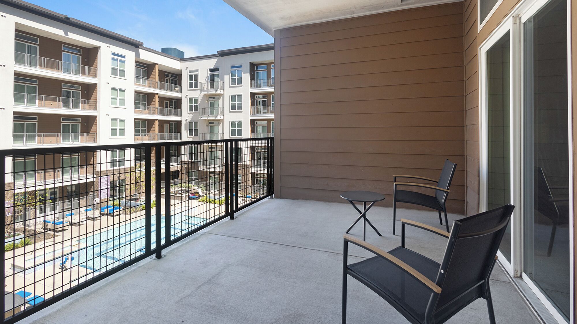 Un balcon donnant sur une piscine et les bâtiments adjacents.
