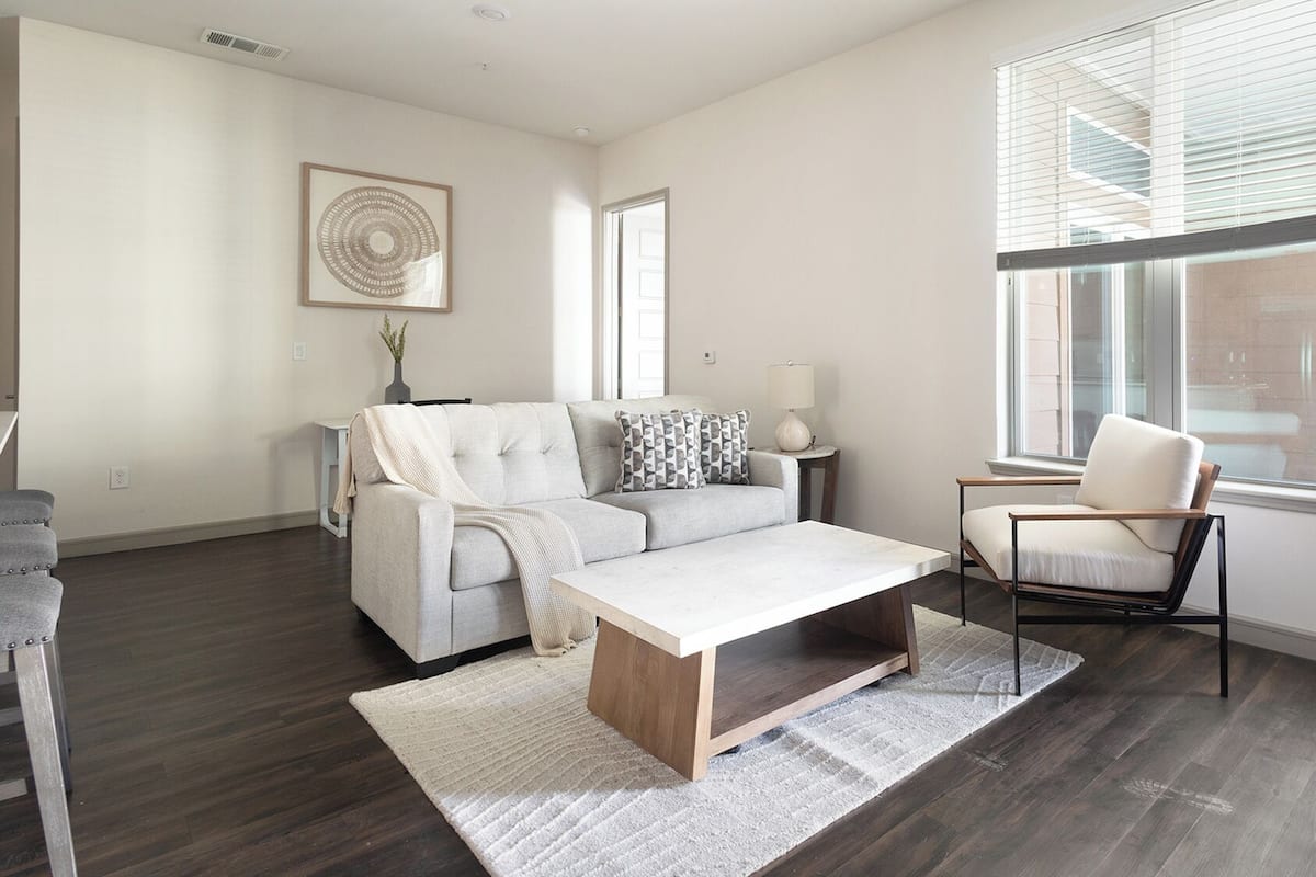 A modern living room with a sofa, coffee table, and armchair, large windows, and a minimalist decor.