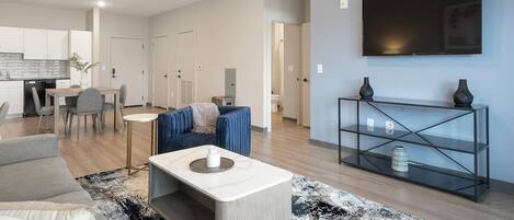 Uma sala de estar moderna com um sofá, mesa de centro e aparador para TV.