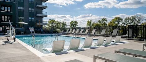 Een seizoensgebonden buitenzwembad, ligstoelen bij het zwembad