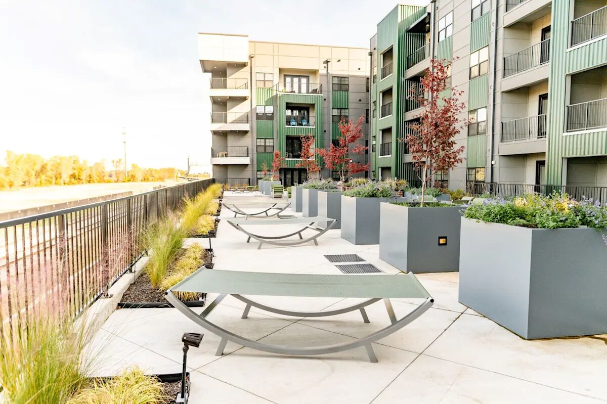 Un edificio de apartamentos moderno con balcones, mobiliario exterior y macetas.