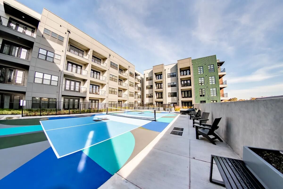 Un edificio residenziale a più piani con balconi, area piscina sul tetto e posti a sedere all'aperto.