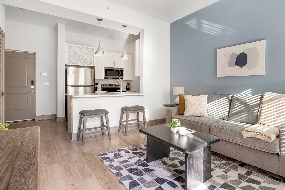 A modern living room with a grey sofa, a coffee table, and a patterned rug.
