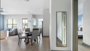 Un salon moderne comprenant un coin repas, une cuisine et une chambre à coucher, cette dernière étant visible à travers une porte ouverte.