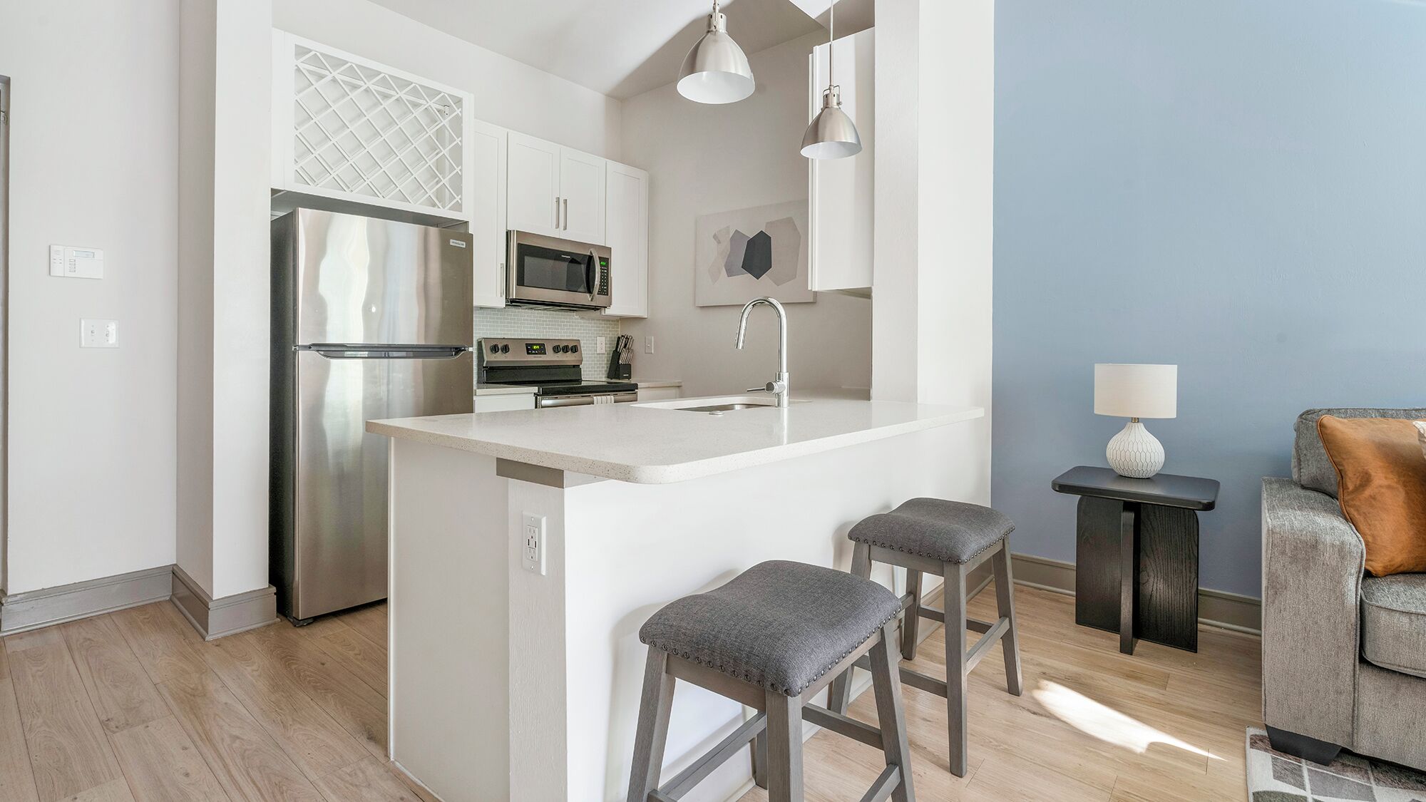 A modern kitchen with a central island, stainless steel appliances, and a bar stool seating area.